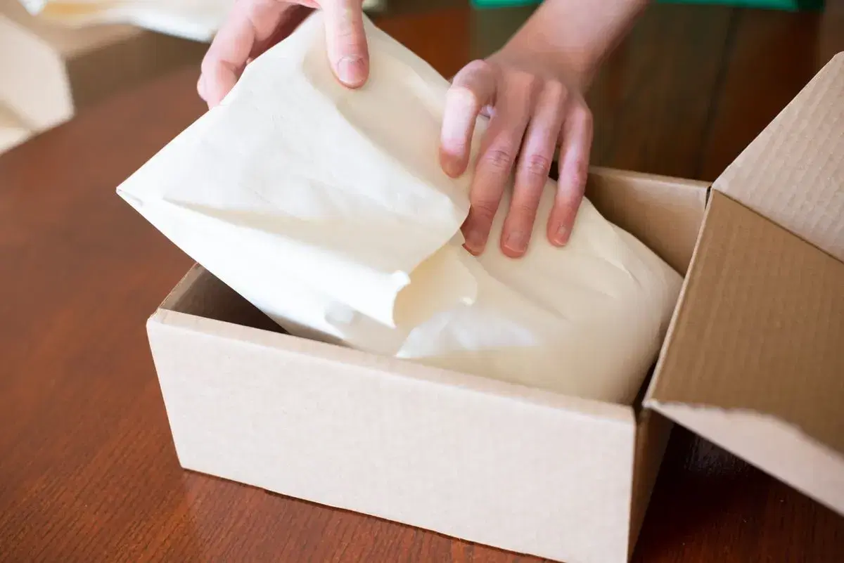 Mãos embalando um pedido em caixa de papelão